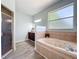 Bright bathroom features a glass enclosed shower, soaking tub, and vanity with wood cabinets at 13013 County Road 561A, Clermont, FL 34715