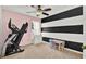 Bedroom with a ceiling fan, striped accent wall, a small table and exercise machine at 1313 Lake Idamere Blvd, Tavares, FL 32778