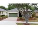 Charming single-story home featuring a landscaped front yard, a welcoming porch, and a light-green garage door at 135 Crepe Myrtle Dr, Groveland, FL 34736