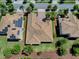 An aerial view displays the property with brick driveway, lush green landscaping, and a solar paneled home next door at 1408 Deuce Cir, Davenport, FL 33896