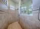 Walk-in tiled shower with a rain shower head, accent tiling, and a shower window at 1408 Deuce Cir, Davenport, FL 33896