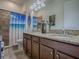 Bathroom featuring a double vanity with granite countertop, updated fixtures, and a decorative shower curtain at 1408 Deuce Cir, Davenport, FL 33896