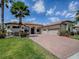Beautiful home with a well-manicured lawn, brick driveway, lush landscaping, and a three-car garage in a sunny setting at 1408 Deuce Cir, Davenport, FL 33896