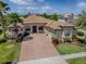 Aerial view of a lovely home with a paver driveway, tile roof, meticulous landscaping, and an attached three-car garage at 1408 Deuce Cir, Davenport, FL 33896