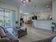 Bright, open living area featuring hardwood floors, comfortable seating, and a view of the kitchen at 1408 Deuce Cir, Davenport, FL 33896