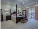 Luxurious main bedroom with a four-poster bed, tray ceiling, and access to the outdoor patio at 1408 Deuce Cir, Davenport, FL 33896