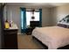 Bedroom boasts neutral paint, a comfy bed, a dresser with mirror, and vibrant blue curtains for a cozy touch at 1420 Kissimmee Ct, Kissimmee, FL 34759