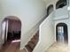 Bright foyer featuring a carpeted staircase, tiled floor, and arched doorways at 1420 Kissimmee Ct, Kissimmee, FL 34759