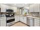Contemporary kitchen boasts sleek appliances, granite countertops, custom white cabinetry, and stylish fixtures at 1536 Barnwell Pl, The Villages, FL 32162