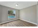 Bright bedroom with a window overlooking the backyard pool, neutral walls and wood-look flooring at 1566 Lawndale Cir, Winter Park, FL 32792