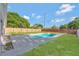 Private backyard featuring a sparkling pool, concrete deck, brick fence and lush green lawn at 1566 Lawndale Cir, Winter Park, FL 32792