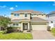 Charming two-story home featuring a brick driveway, neutral siding, manicured landscaping, and an attached two-car garage at 161 Williamson Dr, Davenport, FL 33897