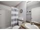 This bathroom features a shower with a gray and white curtain, a white toilet, and a sink at 1733 Oakville Pl, The Villages, FL 32162