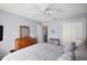 This is a bedroom with wood dresser, gray walls, ceiling fan, and a view to an adjacent room at 1733 Oakville Pl, The Villages, FL 32162