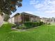 Backyard view highlighting lush green lawn, landscaping, and a screened patio with an outdoor seating area at 17769 Se 121St Terrace Rd, Summerfield, FL 34491