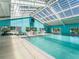 The community indoor pool features a vaulted ceiling, ample lighting, and tables and chairs for relaxing at 17769 Se 121St Terrace Rd, Summerfield, FL 34491
