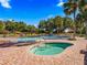 A community pool and jacuzzi surrounded by patio with chairs and umbrellas at 17769 Se 121St Terrace Rd, Summerfield, FL 34491