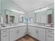 Bright bathroom featuring dual sinks with white cabinetry, stylish fixtures, and light wood floors at 1804 Estafana Way, The Villages, FL 32159
