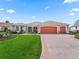 View of a home with a well manicured lawn and a two-car garage from a low angle at 1804 Estafana Way, The Villages, FL 32159