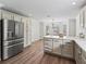 Bright kitchen featuring white cabinetry, quartz countertops, stainless steel appliances and hardwood floors at 1804 Estafana Way, The Villages, FL 32159
