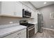 Bright kitchen featuring stainless steel appliances, white cabinets, and marble countertops at 1940 Dempsey Ln, The Villages, FL 32163