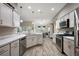 Open kitchen boasts stainless steel appliances, light wood floors and white cabinets at 1940 Dempsey Ln, The Villages, FL 32163