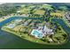 A sprawling aerial view of the community clubhouse, pool, tennis courts, and surrounding lakes and greenery at 1966 Wallingford Loop, Mount Dora, FL 32757