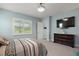 Comfortable bedroom featuring a mounted TV, dresser, and bright window with white shutters at 1966 Wallingford Loop, Mount Dora, FL 32757
