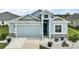 Charming single-Gathering home featuring a well-manicured lawn, light blue exterior, and attached two-car garage at 1966 Wallingford Loop, Mount Dora, FL 32757