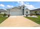 Inviting single-Gathering home with a well-manicured lawn, light blue exterior, and an attached two-car garage at 1966 Wallingford Loop, Mount Dora, FL 32757