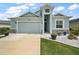 Beautiful single-Gathering home featuring a well-manicured lawn, light blue exterior, and attached two-car garage at 1966 Wallingford Loop, Mount Dora, FL 32757