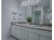 Bathroom features a white double sink vanity with granite countertops, lighting, and a large mirror at 2103 Patino Ln, The Villages, FL 32159