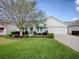 Charming white home with well-manicured lawn, mature tree, green awnings and attached garage at 2103 Patino Ln, The Villages, FL 32159