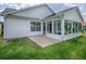 Rear exterior view of home with sunroom and small concrete patio at 2103 Patino Ln, The Villages, FL 32159