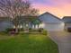 Charming single-story home with a well-manicured lawn, mature tree, and attached two car garage at 2103 Patino Ln, The Villages, FL 32159