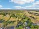 Drone shot displays a spacious property bordering a highway, featuring ample greenery, trees, and a neighboring golf course at 23519 State Road 44, Eustis, FL 32736