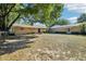 Expansive backyard view showcasing the home's exterior, mature trees, and partially fenced yard at 23519 State Road 44, Eustis, FL 32736