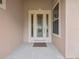 Close-up of a decorative front door with sidelights, a welcome mat, and neutral paint at 26301 Sackamaxon Dr, Sorrento, FL 32776