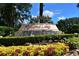 Welcoming entrance to Highland Lakes featuring colorful landscaping and a charming water feature at 26535 Deuce Ct, Leesburg, FL 34748