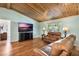 Comfortable living room featuring hardwood floors, a leather sofa, and a mounted TV at 26535 Deuce Ct, Leesburg, FL 34748