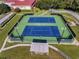 Aerial view of meticulously maintained tennis courts with ample lighting and viewing area surrounded by mature landscaping at 26535 Deuce Ct, Leesburg, FL 34748