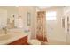 Well-lit bathroom featuring granite countertop and shower-tub combination with palm-themed shower curtain at 27024 Old English Ct, Leesburg, FL 34748