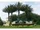 An inviting community entrance is marked by palm trees and attractive signage at 27024 Old English Ct, Leesburg, FL 34748
