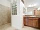 Walk-in shower with glass block window and tile surround plus a double sink vanity at 2992 Hicks Pl, The Villages, FL 32163
