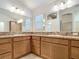 Main bathroom features double sinks, a large mirror, wood cabinets, and tile flooring at 2992 Hicks Pl, The Villages, FL 32163
