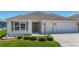 Front exterior featuring a manicured lawn and a two-car garage at 2992 Hicks Pl, The Villages, FL 32163
