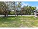 Expansive backyard featuring lush green grass, mature trees, a white fence and swing set, perfect for outdoor activities at 301 Brookstone Ln, Fruitland Park, FL 34731