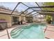 Sparkling swimming pool with a screened enclosure, patio area, and outdoor cooking space at 35138 Silver Oak Dr, Leesburg, FL 34788