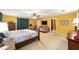 Large primary bedroom with yellow walls, a ceiling fan, comfortable seating, and an en-suite bathroom offers a private retreat at 400 Sw 35Th St, Ocala, FL 34471
