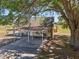 Exterior view of carport and additional structure on property shaded by a mature tree at 4635 Brantley Rd, Groveland, FL 34736